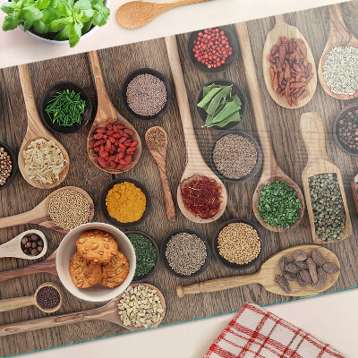 Glas-Schneidebrett mit Motiv aus Gewürzen und Kräutern in Holzlöffeln