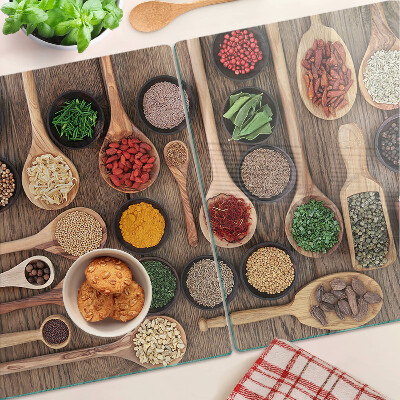 Glas-Schneidebrett mit Motiv aus Gewürzen und Kräutern in Holzlöffeln