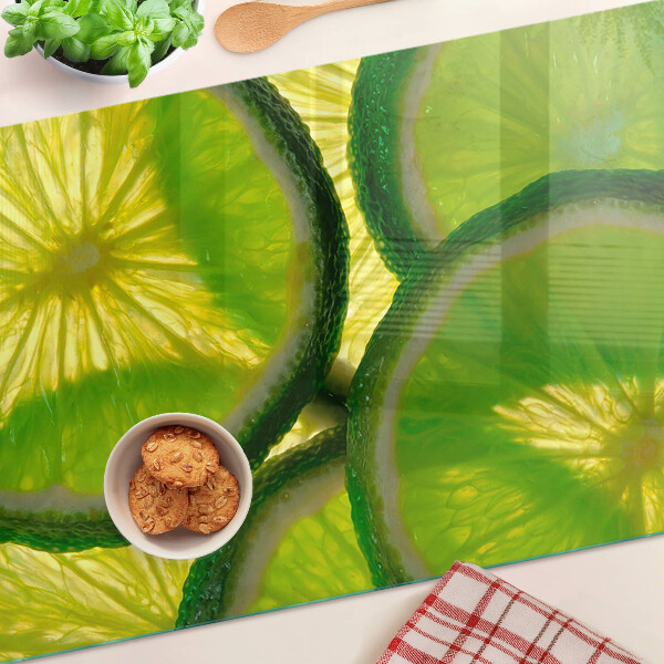 Schneidebrett mit Limettenscheiben auf grünem Hintergrund