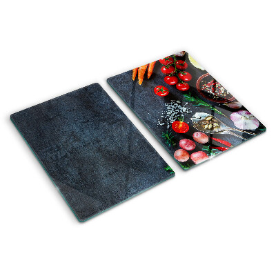 Glas-Schneidebrett mit Motiv von Gemüse und Gewürzen auf dunklem Hintergrund