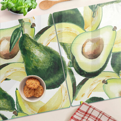 Glas-Schneidebrett mit Avocado-Motiv und Blättern im Hintergrund