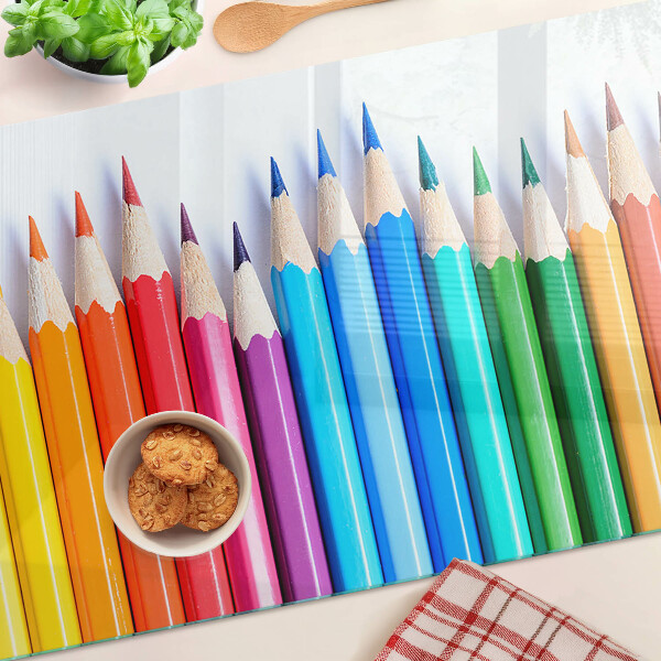 Schneidebrett Glas mit farbigen Stiften nebeneinander angeordnet