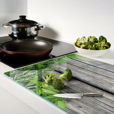 Glas-Schneidebrett mit Motiv grüner Kräuter auf Holzuntergrund