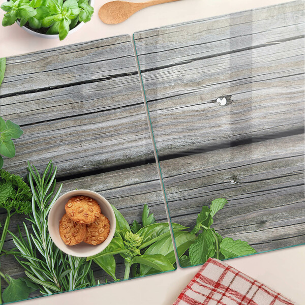 Glas-Schneidebrett mit Motiv grüner Kräuter auf Holzuntergrund