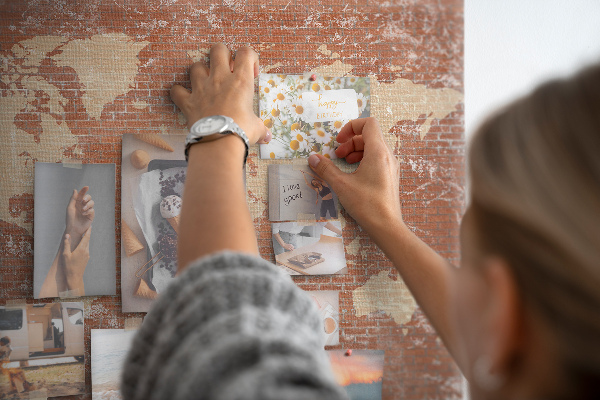 Korktafel mit Weltkartenmotiv vor einer Backsteinmauer