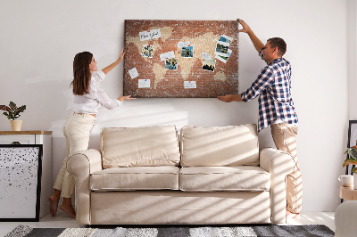 Korktafel mit Weltkartenmotiv vor einer Backsteinmauer