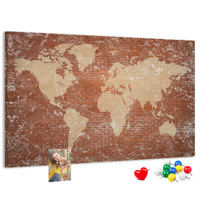 Korktafel mit Weltkartenmotiv vor einer Backsteinmauer