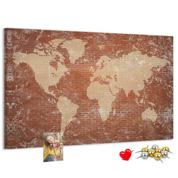 Korktafel mit Weltkartenmotiv vor einer Backsteinmauer