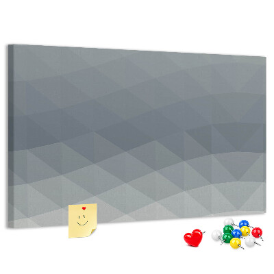 Korktafel mit geometrischen Graustufendreiecken im Hintergrund