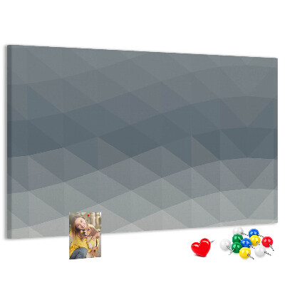 Korktafel mit geometrischen Graustufendreiecken im Hintergrund