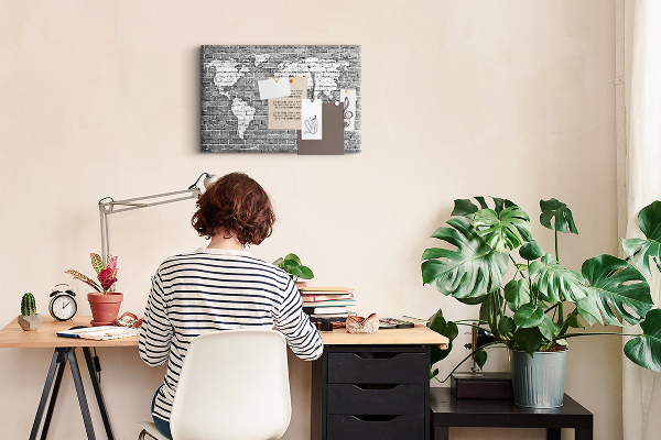 Korktafel mit Motiv Weltkarte an einer Backsteinmauer