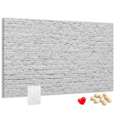 Korktafel mit weißem Backsteinmauer-Motiv und bunten Reißzwecken