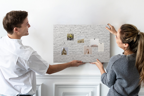 Korktafel mit weißem Backsteinmauer-Motiv und bunten Reißzwecken